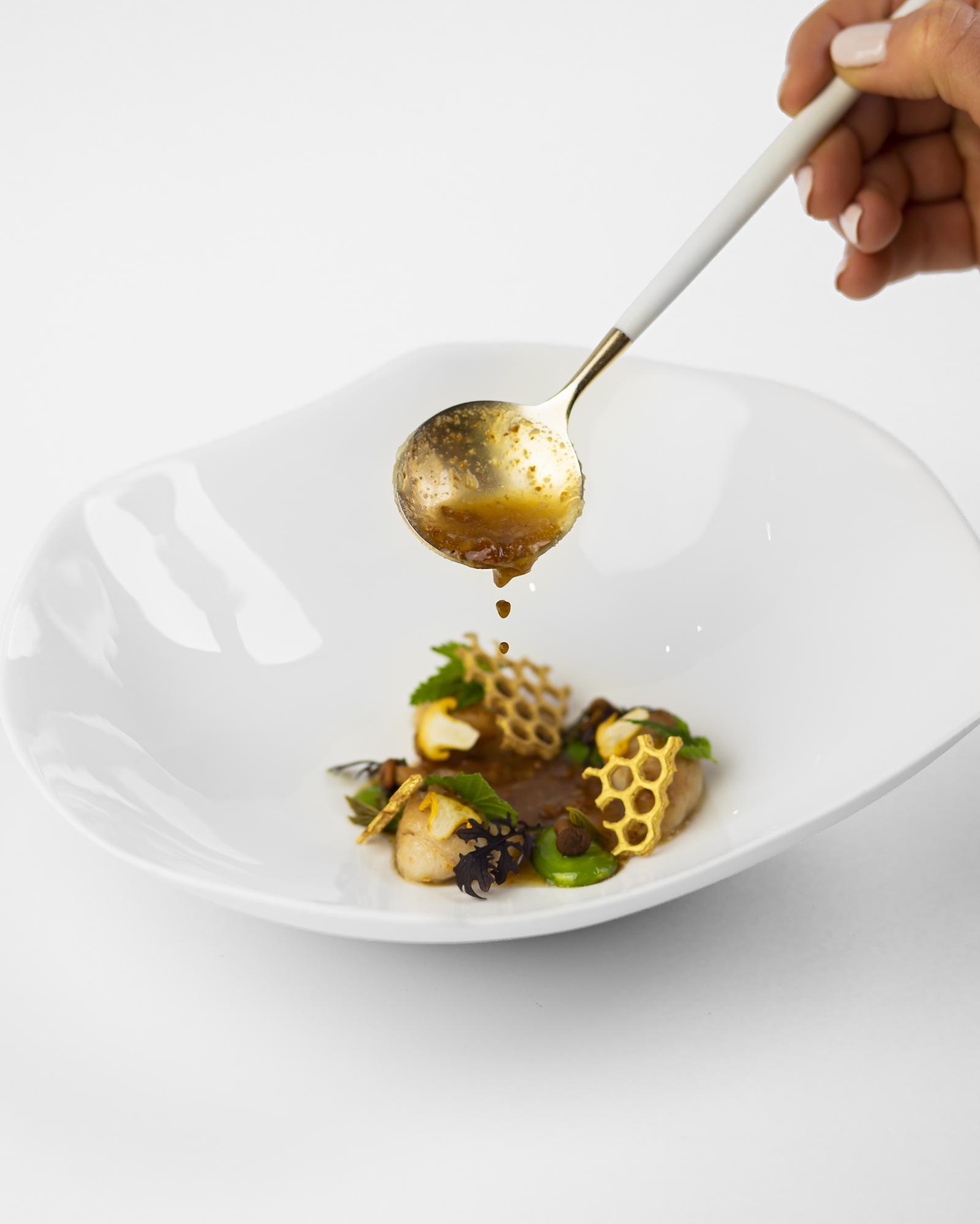 Chef plating a refined dish on a dark table